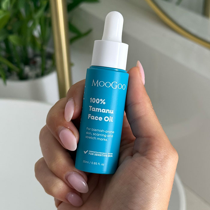 MooGoo Tamanu Face Oil bottle held in front of a leafy background, reduces scars, stretch marks and blemishes.
