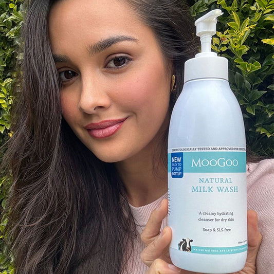 Woman smiling while holding MooGoo Natural Milk Wash, gentle hydrating cleanser for sensitive face and body