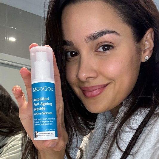 happy woman holding MooGoo Amplified Anti-Ageing Peptide Active Serum 25ml, her expression lines are diminished and reduced.