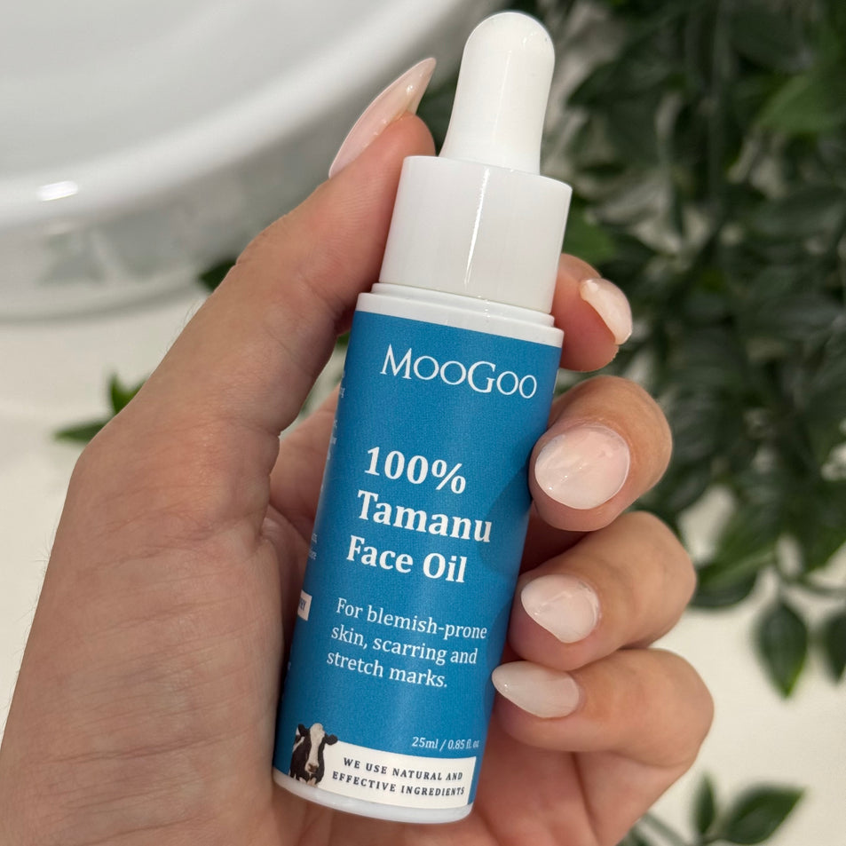 MooGoo Tamanu Face Oil bottle held in front of a leafy background, reduces scars, stretch marks and blemishes.