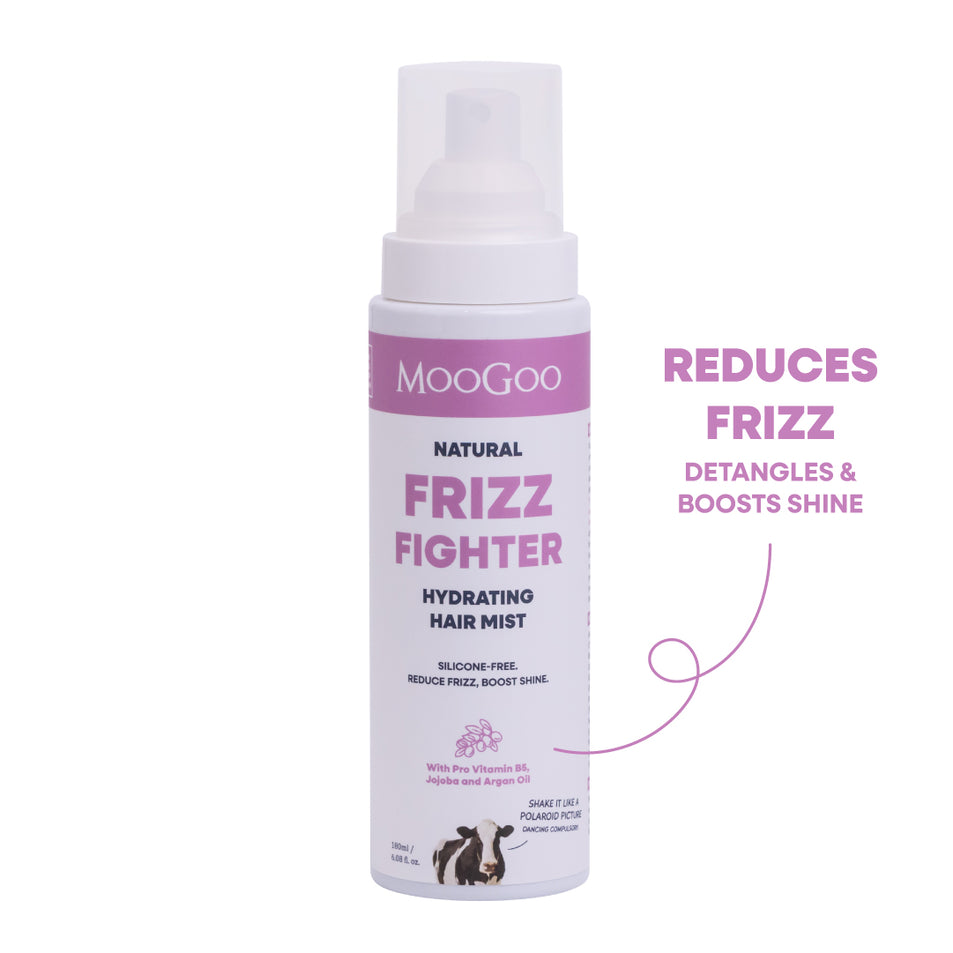 MooGoo Natural Frizz Fighter Hydrating Hair Mist in a white spray bottle with pink and black text, shown on a white background with a purple callout reading 'REDUCES FRIZZ DETANGLES & BOOSTS SHINE'. Silicone-free frizz spray with jojoba oil and pro vitamin B5. 