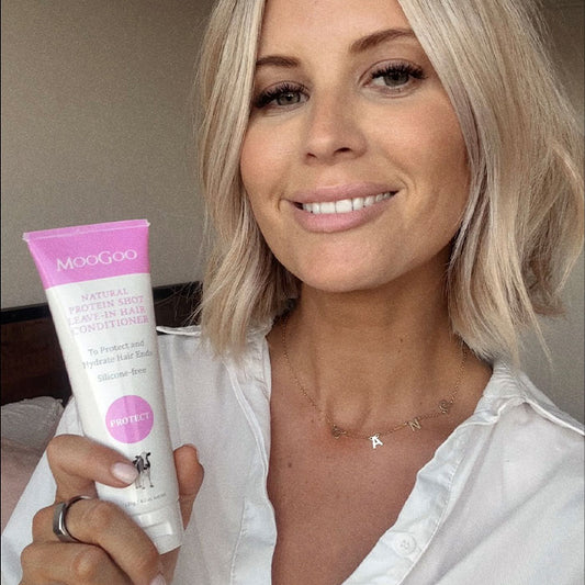 Close-up of MooGoo Protein Shot Leave-In Conditioner tube held by model, natural formula for stronger and healthier hair