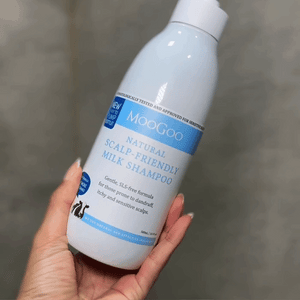Woman applying MooGoo Milk Shampoo for sensitive scalp, dermatologist-approved scalp care, SLS free.