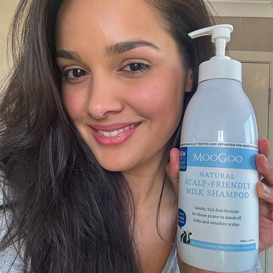 Woman smiling while holding MooGoo Natural Milk Wash, gentle hydrating cleanser for sensitive face and body