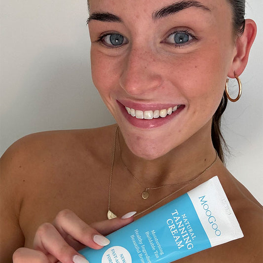 Smiling woman holding MooGoo Natural Tanning Cream tube, fast-developing self tan with natural oils and hyaluronic acid for a glowing bronze