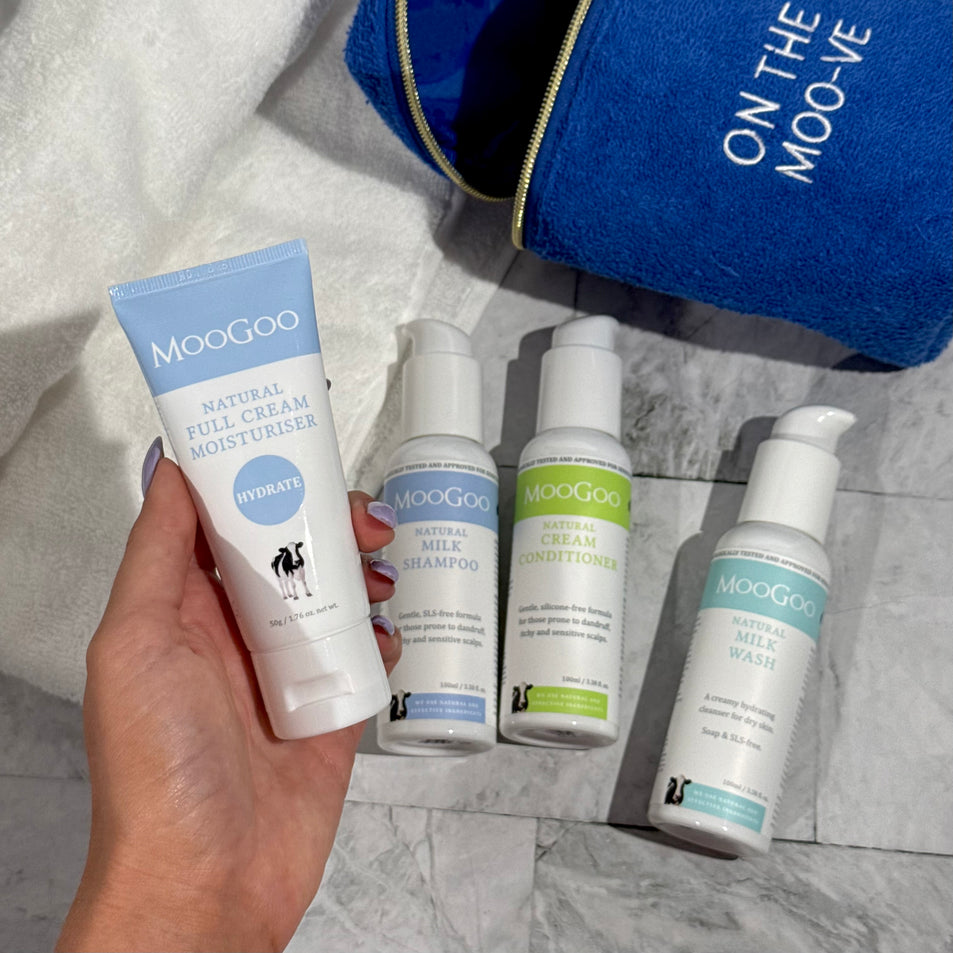 MooGoo Travel Pack on tiles with a white towel in the background, including travel-sized Milk Shampoo, Cream Conditioner, Milk Wash and Full Cream Moisturiser - ideal for sensitive skin, hydration and scalp health