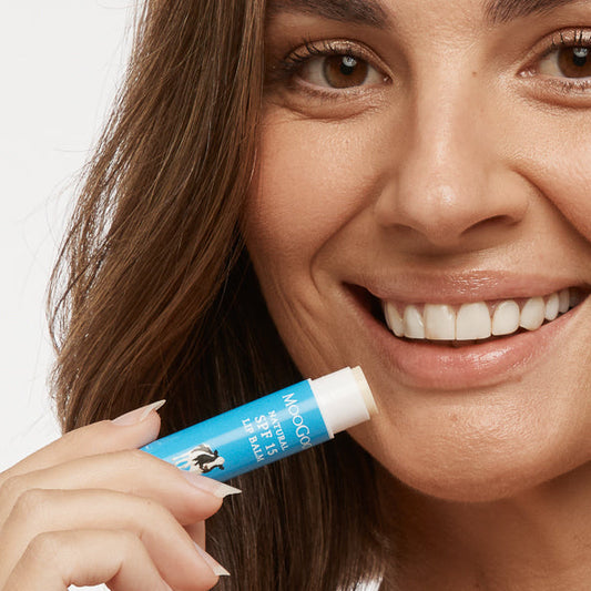 Smiling woman MooGoo Natural SPF 15 Lip Balm, hydrating sun protective lip care with zinc oxide for smooth, moisturised lips.